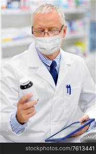medicine, healthcare and technology concept - senior apothecary wearing face protective medical mask for protection from virus disease with tablet pc computer at pharmacy. old apothecary in mask with tablet pc at pharmacy