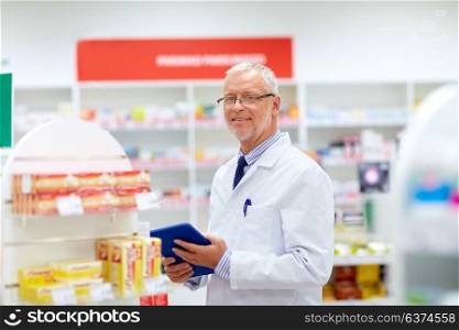 medicine, healthcare and technology concept - senior apothecary with tablet pc computer at pharmacy. senior with tablet pc at pharmacy