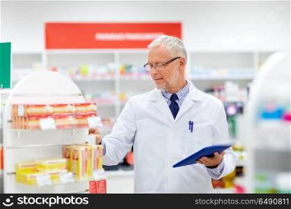 medicine, healthcare and technology concept - senior apothecary with tablet pc computer at pharmacy. senior with tablet pc at pharmacy. senior with tablet pc at pharmacy