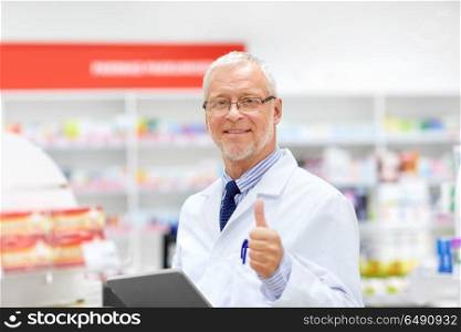 medicine, healthcare and technology concept - senior apothecary with tablet pc computer at pharmacy. senior with tablet pc at pharmacy. senior with tablet pc at pharmacy