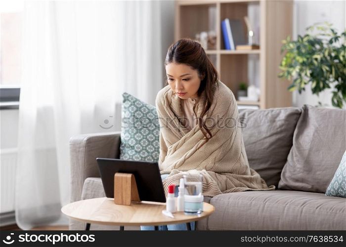 medicine, healthcare and technology concept - sick young asian woman having video call or online consultation on tablet pc computer at home. sick woman having video call on tablet pc at home