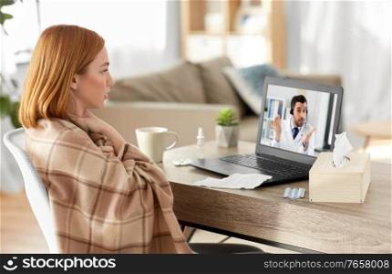 medicine, healthcare and technology concept - sick young woman having video call or online consultation with doctor on laptop computer at home and coughing. sick woman having video call with doctor on laptop