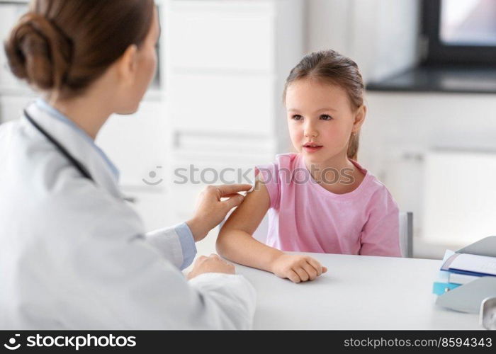 medicine, healthcare and vaccination concept - female doctor or pediatrician disinfecting arm skin of little girl patient at clinic. doctor preparing girl patient for vaccination