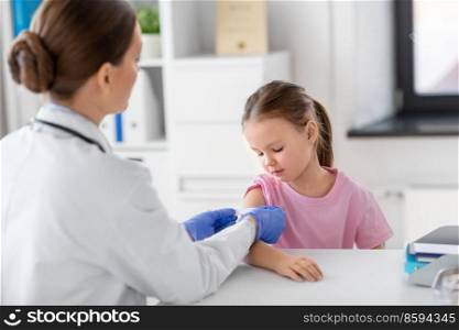 medicine, healthcare and vaccination concept - female doctor or pediatrician talking to little girl patient on medical exam at clinic. female doctor and little girl patient at clinic