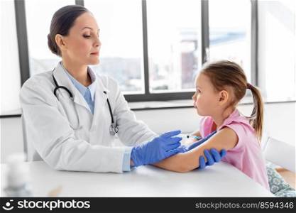 medicine, healthcare and vaccination concept - female doctor or pediatrician with syringe making vaccine injection to little girl patient at clinic. doctor with syringe making injection to girl