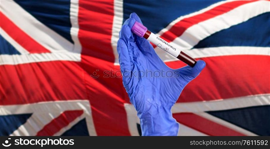 medicine, healthcare and virus concept - close up of hand in protective medical glove holding beaker with coronavirus blood test over flag of united kingdom. hand holding beaker with coronavirus blood test