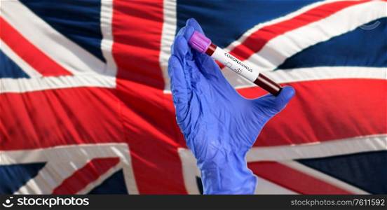 medicine, healthcare and virus concept - close up of hand in protective medical glove holding beaker with coronavirus blood test over flag of united kingdom. hand holding beaker with coronavirus blood test