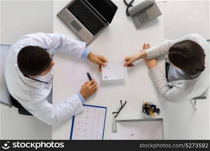 medicine, healthcare, cardiology and people concept - doctor giving prescription to young patient woman at hospital. doctor giving prescription to patient at hospital