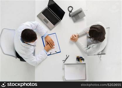 medicine, healthcare, cardiology and people concept - doctor with cardiogram on clipboard and young patient woman meeting at hospital. doctor with cardiogram and patient at hospital