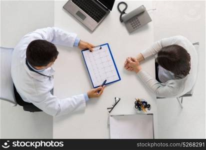 medicine, healthcare, cardiology and people concept - doctor with cardiogram on clipboard and young patient woman meeting at hospital. doctor with cardiogram and patient at hospital