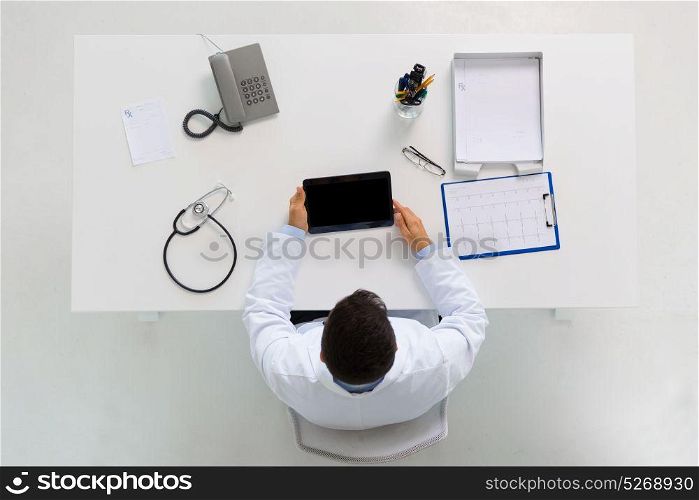 medicine, healthcare, cardiology and people concept - doctor with tablet pc computer and cardiogram sitting at table in clinic. doctor with tablet pc and cardiogram at clinic