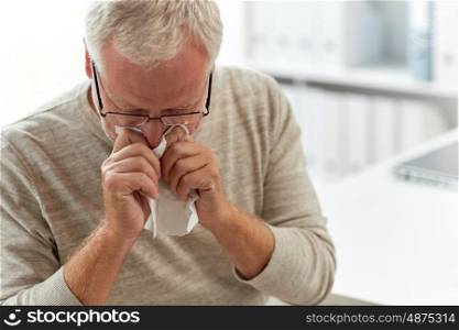 medicine, healthcare, flu and people concept - senior man blowing nose with napkin at medical office at hospital