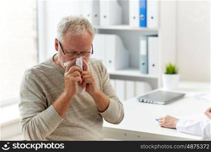 medicine, healthcare, flu and people concept - senior man blowing nose with napkin and doctor with clipboard writing at medical office at hospital