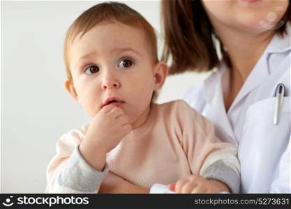 medicine, healthcare, pediatry and people concept - doctor or pediatrician holding baby on medical exam at clinic. doctor or pediatrician with baby on medical exam