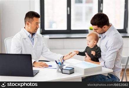 medicine, healthcare, pediatry and people concept - father with baby and doctor at medical office in hospital. father with baby and doctor at clinic