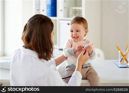 medicine, healthcare, pediatry and people concept - happy doctor or pediatrician and baby playing with stethoscope on medical exam at clinic. happy doctor or pediatrician with baby at clinic