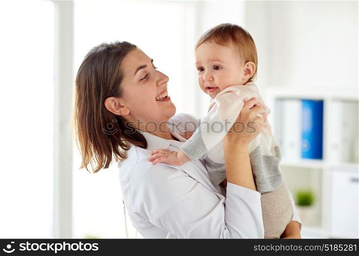 medicine, healthcare, pediatry and people concept - happy doctor or pediatrician holding baby on medical exam at clinic. happy doctor or pediatrician with baby at clinic