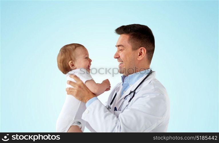 medicine, healthcare, pediatry and people concept - happy doctor or pediatrician holding baby on medical exam over blue background. happy doctor or pediatrician with baby over blue