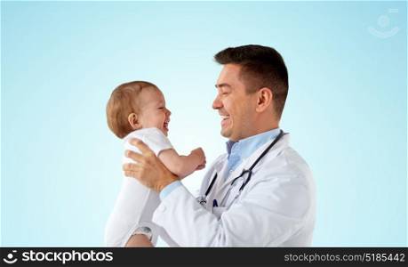 medicine, healthcare, pediatry and people concept - happy doctor or pediatrician holding baby on medical exam over blue background. happy doctor or pediatrician with baby over blue
