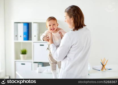 medicine, healthcare, pediatry and people concept - happy doctor or pediatrician holding baby on medical exam at clinic. doctor or pediatrician holding baby at clinic