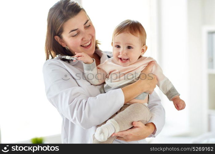 medicine, healthcare, pediatry and people concept - happy doctor or pediatrician holding baby on medical exam at clinic. doctor or pediatrician holding baby at clinic