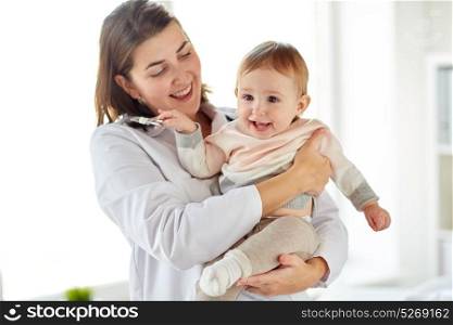 medicine, healthcare, pediatry and people concept - happy doctor or pediatrician holding baby on medical exam at clinic. doctor or pediatrician holding baby at clinic