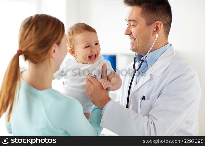 medicine, healthcare, pediatry and people concept - happy doctor with stethoscope listening to baby on medical exam at clinic. doctor with stethoscope and baby at clinic