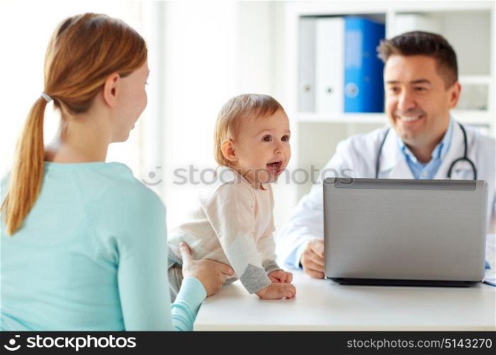 medicine, healthcare, pediatry and people concept - happy woman with baby and doctor with laptop computer at clinic. woman with baby and doctor with laptop at clinic