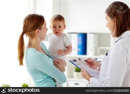 medicine, healthcare, pediatry and people concept - happy woman with baby and doctor with clipboard at clinic. happy woman with baby and doctor at clinic