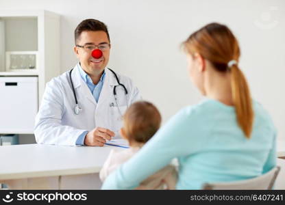 medicine, healthcare, pediatry and red nose day concept - happy woman with baby and doctor at clinic. baby with mother at doctor on red nose day