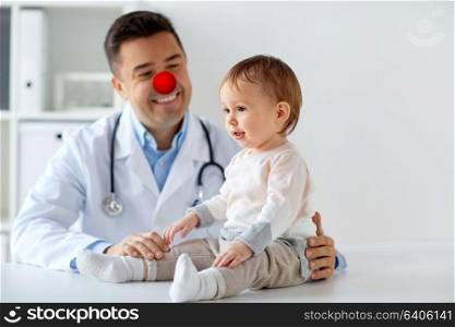 medicine, healthcare, pediatry and red nose day concept - sweet baby girl and doctor or pediatrician on medical exam at clinic. happy baby girl at doctor on red nose day