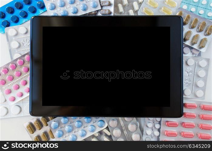 medicine, healthcare, pharmacy and technology concept - tablet pc computer with different pills and capsules of drugs. tablet pc with pills and capsules of drugs