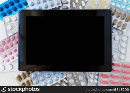 medicine, healthcare, pharmacy and technology concept - tablet pc computer with different pills and capsules of drugs. tablet pc with pills and capsules of drugs