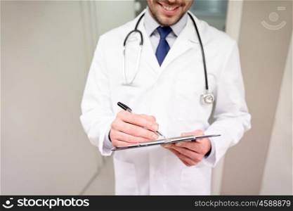 medicine, healthcare, profession and people concept - close up of happy smiling male doctor with clipboard and stethoscope at hospital