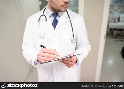 medicine, healthcare, profession and people concept - close up of male doctor with clipboard and stethoscope at hospital