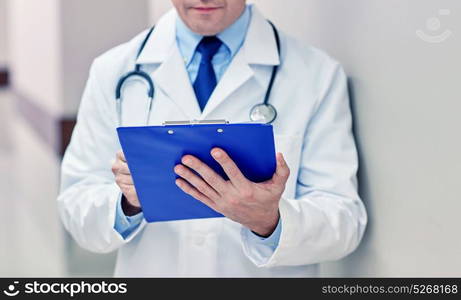 medicine, healthcare, profession and people concept - close up of male doctor with clipboard at hospital. close up of doctor with clipboard at hospital