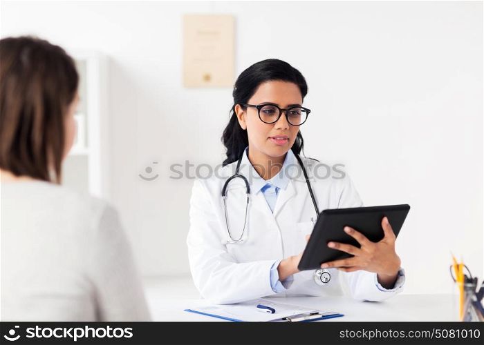 medicine, healthcare, technology and people concept - doctor with tablet pc computer and woman patient meeting at hospital. doctor with tablet pc and woman at hospital