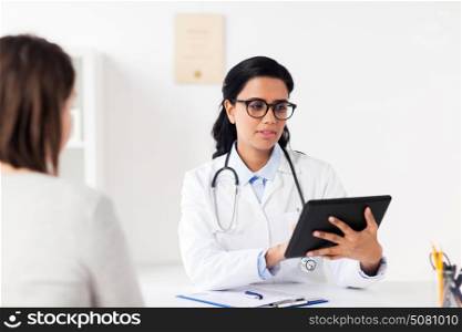 medicine, healthcare, technology and people concept - doctor with tablet pc computer and woman patient meeting at hospital. doctor with tablet pc and woman at hospital