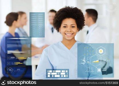 medicine, healthcare, technology and people concept - happy african american female doctor or nurse over group of medics at hospital. happy african american female doctor at hospital