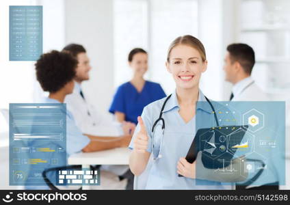 medicine, healthcare, technology and people concept - happy female doctor with clipboard showing thumbs up gesture at hospital. happy doctor at hospital showing thumbs up gesture