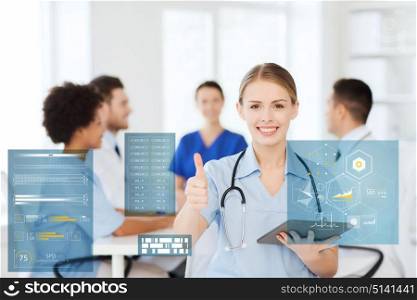 medicine, healthcare, technology and people concept - happy female doctor with tablet pc computer over group of medics meeting at hospital showing thumbs up gesture. doctor with tablet pc at clinic showing thumbs up