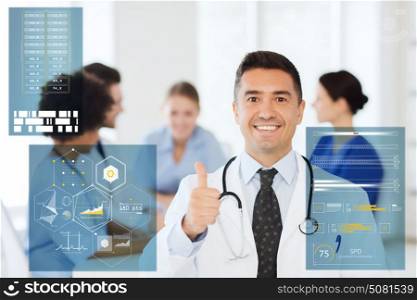 medicine, healthcare, technology and people concept - happy male doctor over group of medics meeting at hospital showing thumbs up gesture. happy doctor showing thumbs up at hospital