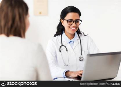 medicine, healthcare, technology and people concept - smiling doctor with laptop computer and woman patient at hospital. doctor with laptop and woman patient at hospital