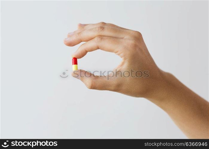 medicine, nutritional supplements and people concept - close up of hand holding capsule of drug. close up of hand holding capsule of medicine