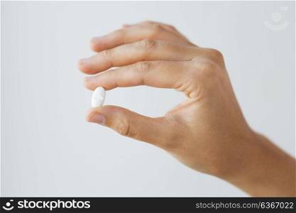 medicine, nutritional supplements and people concept - close up of hand holding pill. close up of hand holding medicine pill