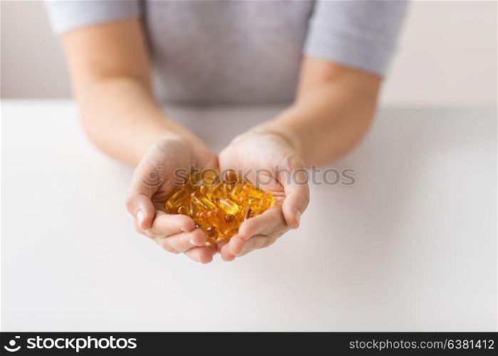 medicine, nutritional supplements and people concept - close up of hands holding cod liver oil capsules. hands holding cod liver oil capsules