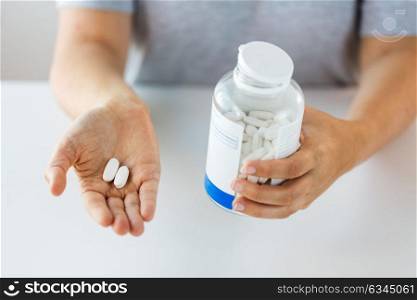 medicine, nutritional supplements and people concept - close up of hands holding pills and jar. close up of hands holding medicine pills and jar