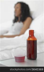 Medicine on bedside table beside woman in bed