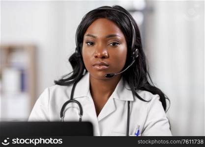medicine, online service and healthcare concept - african american female doctor or nurse with headset and laptop at hospital. african doctor with headset and laptop at hospital