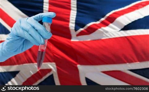 medicine, pandemic and virus concept - close up of hand holding test tube with coronavirus blood test over flag of great britain background. hand holding test tube with coronavirus blood test
